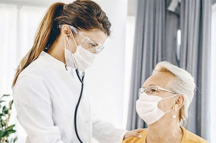 Une doctoresse avec une patiente âgée, toutes les deux masquées.