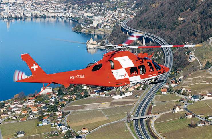 Hélicoptère de la REGA survolant un lac.